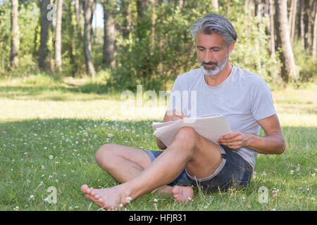 gut aussehender Mann malen eine Frühlingslandschaft Stockfoto