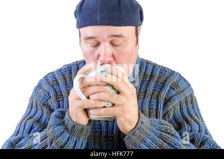 Applying Mann im blauen Pullover und Baskenmütze heißen Getränk trinken Stockfoto