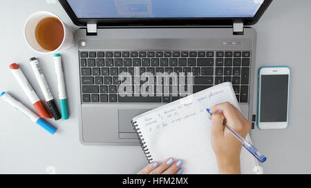 Weibliche Hände machende Notizen im Notizbuch mit Stift Stockfoto