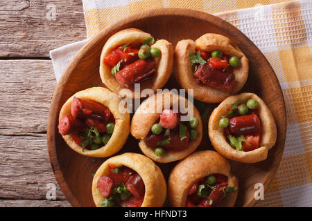 Yorkshire Pudding gefüllt mit Wurst und grüne Erbsen auf einem Teller mit einer Tabelle Großaufnahme. horizontale Ansicht von oben Stockfoto