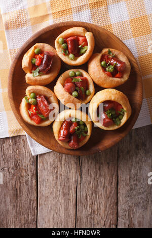 Yorkshire Pudding gefüllt mit Wurst und grüne Erbsen auf einem Teller mit einer Tabelle Großaufnahme. vertikale Ansicht von oben Stockfoto