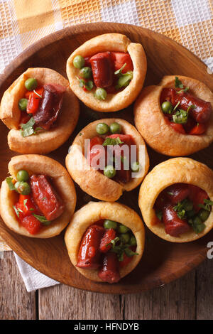 Yorkshire Pudding gefüllt mit Wurst und Gemüse auf einem Teller mit einer Tabelle Großaufnahme. vertikale Ansicht von oben Stockfoto