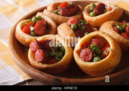 Köstlichen Yorkshire Pudding gefüllt mit Wurst und grüne Erbsen Nahaufnahme. horizontale Stockfoto