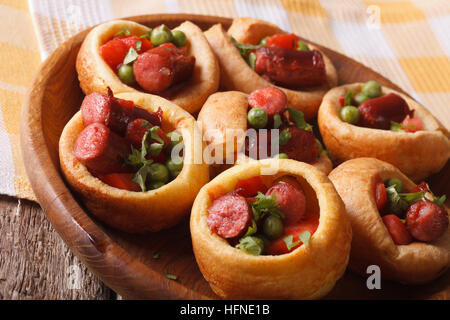 rustikale Yorkshire Pudding gefüllt mit Wurst und grüne Erbsen Nahaufnahme. horizontale Stockfoto