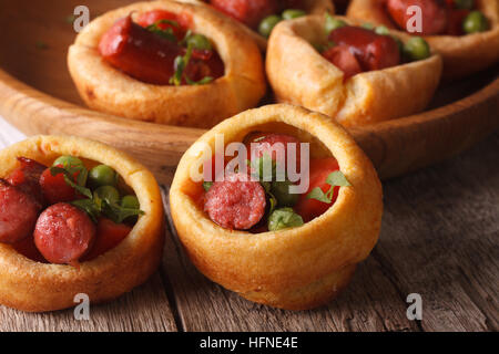 Yorkshire Pudding gefüllt mit Wurst und Gemüse Makro auf dem Tisch. Horizontale Stockfoto