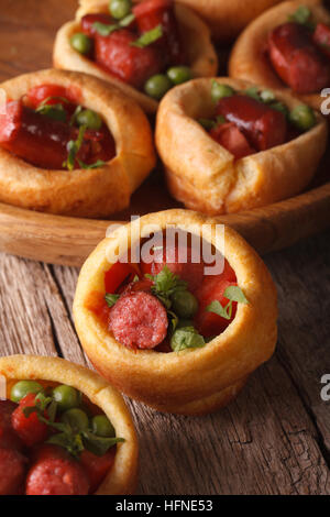 Yorkshire Pudding gefüllt mit Wurst und Gemüse Nahaufnahme auf dem Tisch. Vertikal Stockfoto