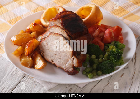 : Sonntag Schweinebraten mit Kartoffeln, Gemüse und Yorkshire Pudding auf der Platte Nahaufnahme. horizontale Stockfoto