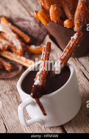 Leckere Kekse Churros getunkt in Schokolade in der Tasse auf dem Tisch. vertikale Stockfoto