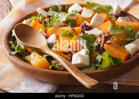 Frischer Salat mit Kaki, Walnüsse, Rucola, Käse und Orangen Nahaufnahme. Horizontal, rustikal Stockfoto
