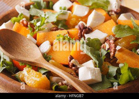 Gesunder Salat mit Kaki, Walnüsse, Rucola, Käse und Orangen Makro. horizontale Stockfoto