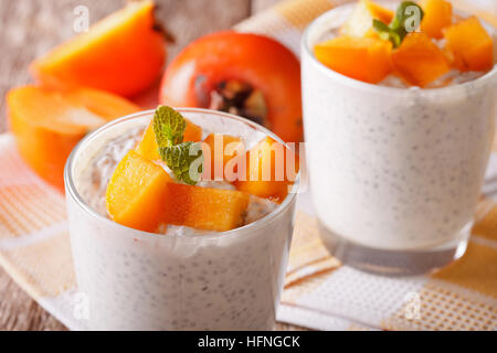 Dessert mit Chiasamen und Persimmon hautnah in einem Glas auf dem Tisch. Horizontale Stockfoto