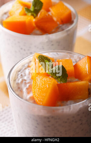 Chia-Samen mit Joghurt und Kaki in einem Glas-Makro. Vertikal Stockfoto