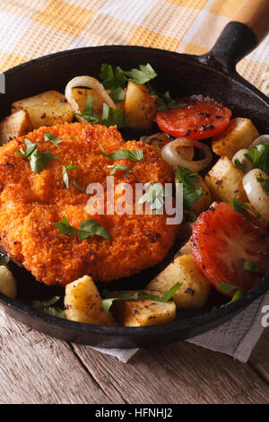 Hausgemachte panierte Deutsch Weiner Schnitzel mit gebratenem Gemüse in einer Pfanne Großaufnahme auf dem Tisch. Vertikal Stockfoto