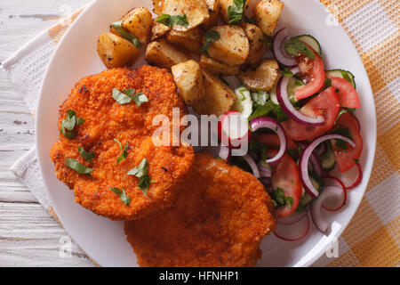 Wiener Schnitzel, Bratkartoffeln und Salat auf den Tisch-Nahaufnahme. horizontale Ansicht von oben Stockfoto