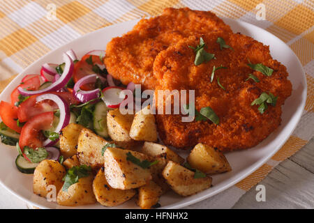 Portion Schnitzel, Bratkartoffeln und Salat auf den Teller Closeup. horizontale Stockfoto