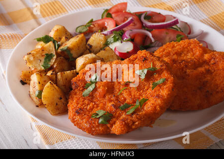 Wiener Schnitzel, Bratkartoffeln und Salat auf den Teller Closeup. Horizontale Stockfoto