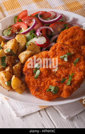 Wiener Schnitzel, Bratkartoffeln und Salat auf den Teller Closeup. vertikale Stockfoto