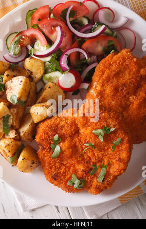 Wiener Schnitzel, Salat und Pommes Frites mit einer Platte Großaufnahme. vertikale Ansicht von oben Stockfoto