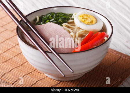 Ramen-Nudeln mit Schweinefleisch, Gemüse und Ei in einer Schüssel hautnah. Horizontale Stockfoto