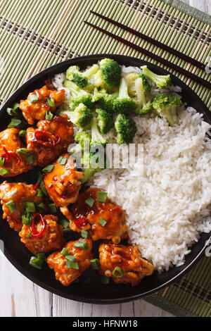 General Tso Chicken mit Reis, Zwiebeln und Brokkoli Nahaufnahme auf dem Tisch. vertikale Ansicht von oben Stockfoto