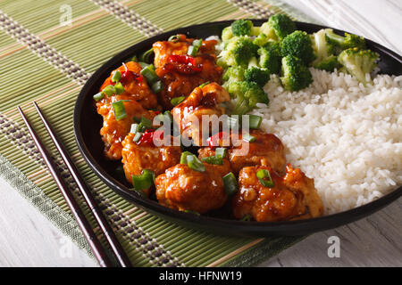 Gourmet-Essen: Huhn general Tso mit Reis, Zwiebeln und Brokkoli Nahaufnahme auf einer Platte. horizontale Stockfoto
