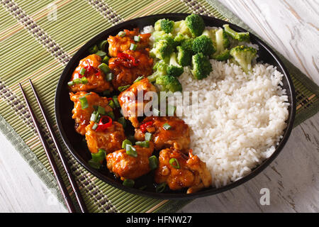 General Tso Chicken mit Reis, Zwiebeln und Brokkoli Nahaufnahme auf einer Platte. horizontale Stockfoto