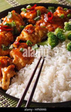 Tso asiatischen Huhn mit Reis und Broccoli Nahaufnahme auf einer Platte. vertikale Stockfoto