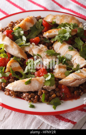 Gesunde braune Linsen mit gegrilltem Hähnchen und Kräuter hautnah auf einem Teller. Vertikal Stockfoto