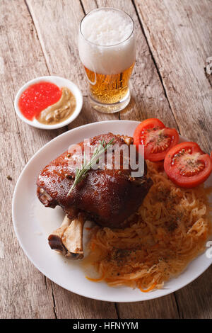 Eisbein: gebackenes Schweinefleisch Schaft und geschmorte Kohl Closeup auf einem Teller und Bier auf dem Tisch. vertikale Stockfoto