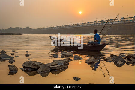 Ein Ruderer sitzt auf seinem Boot bei Sonnenuntergang am Fluss Damodar nahe Durgapur Barrage, West Bengal, Indien. Stockfoto