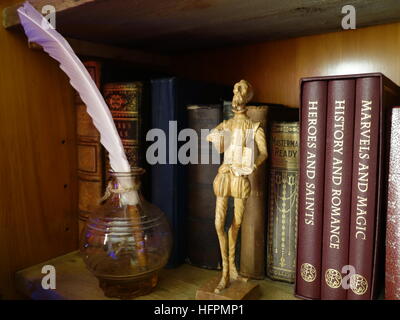 Alte Bücher in einem Regal zusammen mit Schnitzwerk von Shakespeare und eine Feder Stockfoto