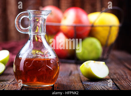 Apfelessig in der Flasche und auf einem Tisch Stockfoto