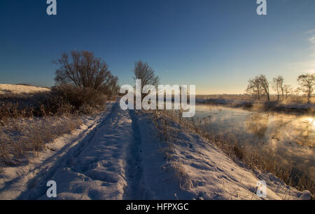 Winterlandschaft mit Fluss, gemeinsamen Reed, blauer Himmel, Schnee, Straße mit Schnee, Sonnenschein. Norwegen, Fredrikstad, Naturschutzgebiet. Dies ist ein wichtiger Bereich für Stockfoto