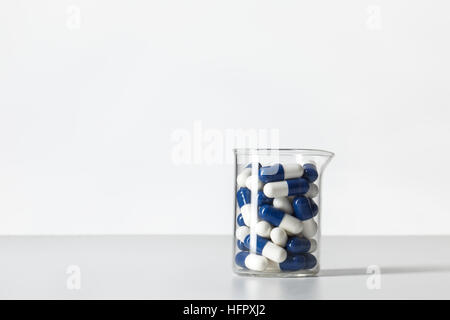Becher-Kolben mit Pillen innen, gedreht im Studio auf weißem Hintergrund Stockfoto