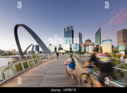 Radfahrer der Elizabeth Quay-Brücke in der Dämmerung mit der Skyline der Stadt darüber hinaus, Perth, Western Australia, Australien Stockfoto
