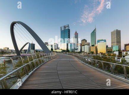 Blick entlang der Elizabeth Quay Fußgängerbrücke, die Skyline der Stadt in der Dämmerung, Perth, Western Australia, Australien Stockfoto