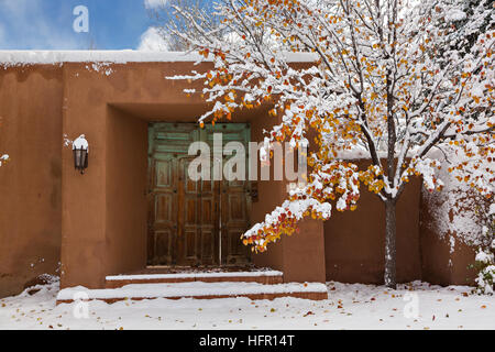 Eine herkömmliche Tür auf eine Adobe-Stil Zuhause im Stadtteil Arroyo Tierra Blanca nach einem Winter Schneefall in Santa Fe, New Mexico. Stockfoto