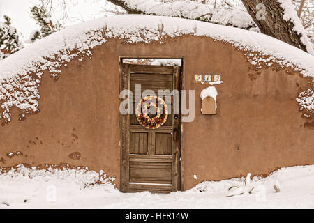 Eine herkömmliche Tür auf eine Adobe-Stil Zuhause im Stadtteil Arroyo Tierra Blanca nach einem Winter Schneefall in Santa Fe, New Mexico. Stockfoto