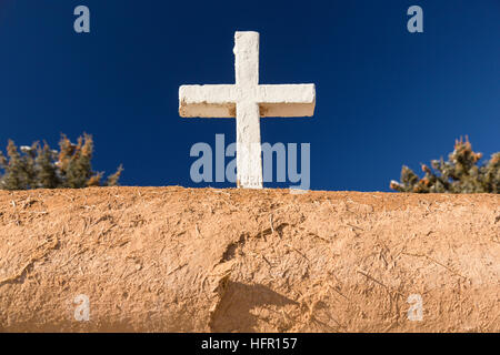 Ein weißes Kreuz auf die historischen San Francisco de Asis Missionskirche in Ranchos de Taos Plaza, Taos, New Mexiko. Die Adobe-Kirche erbaut im Jahre 1772 und berühmt geworden in Gemälde des Künstlers Georgia O'Keeffe. Stockfoto