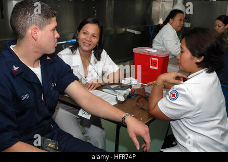 060531-N-3931M-012 Zamboanga, Philippinen (31. Mai 2006) - Krankenschwestern für die philippinischen nationalen Rotkreuz, nimmt einen Temperaturwert und andere wichtige Informationen aus der Navy Petty Officer 3rd Class Christopher Orr aus San Diego, Kalifornien, während eine rote Kreuz Blut Fahrt an Bord der US Military Sealift Command (MSC)-Lazarettschiff USNS Mercy (T-AH 19) bei einem Besuch der Stadt bei einem geplanten humanitären Besuch. Am 17. September 1947 als ein Mitglied der Liga der Rotkreuz- und Rothalbmond-Föderation zugelassen, unterstützt philippinischen nationalen Roten Kreuzes die Regierung zu Soforthilfe für die Opfer in Stockfoto