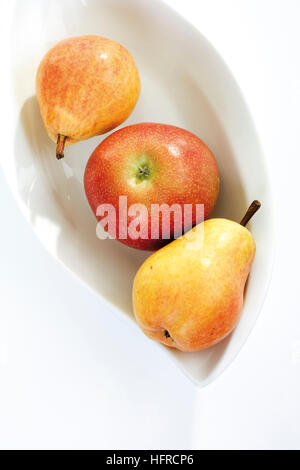 Rote und gelbe Früchte, Apfel und zwei Birnen in einer Obstschale Stockfoto