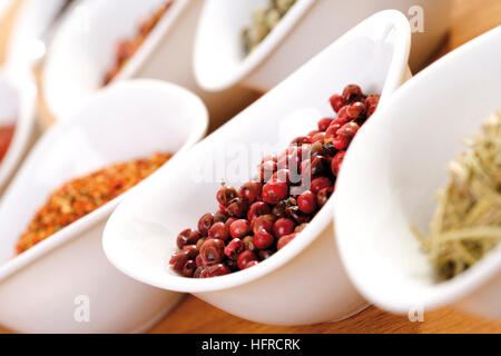 Schalen mit verschiedenen Gewürzen, mit rosa Pfeffer im Fokus Stockfoto