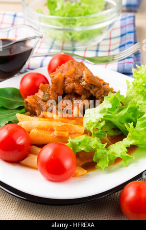 Detail des Kochens Stücke von geschmortem Rindfleisch, Penne-Nudeln, Tomaten und Kräuter Nahaufnahme mit geringen Schärfentiefe Stockfoto