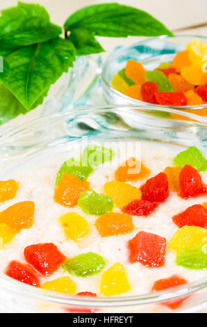 Ansicht-close-up auf Haferflocken mit bunten kandierten Früchten in eine Glasschüssel auf den Tisch für ein gesundes Frühstück mit geringer Tiefe des Feldes Stockfoto