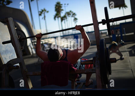 Mann tut Langhantel-Bankdrücken in Outdoor Gym in Venice Beach, Kalifornien. Stockfoto