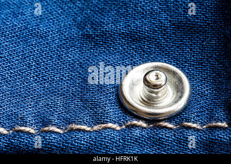Jeans-Textur mit Nieten und Faden hautnah. Blue Denim Stoff Hintergrund. Stockfoto