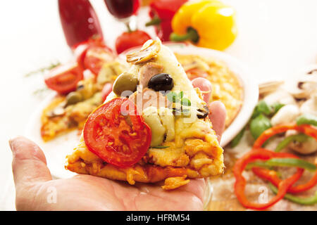 Hand, die ein Stück vom Thunfisch, Artischocken, Tomaten- und Olivenöl pizza Stockfoto