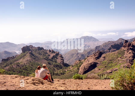 Ein junges Paar/Wanderer bewundern atemberaubende Ausblicke vom Roque Nublo Berg, eine der vulkanischen Felsen auf der Insel Gran Canaria, Kanarische Inseln, Sp Stockfoto