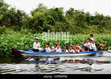 Kleines Boot mit Schulkindern entwässert schwimmende Dorf der Sangkhae - Sangker River Battambang Provinz Cambodia.The Tonle Sap See (reichsten See zum Angeln in der Welt) in den Mekong-Fluss in Phnom Penh. Die kambodschanische Bevölkerung hat auch für das einzigartige Ökosystem des Sees mit schwimmenden angepasst (Fischer-Fischerei) Dörfer und gestelzt Häuser. Stockfoto