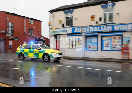 Ein North West Ambulance Service-Fahrzeug auf dem Weg zu einem weiteren Vorfall geht die Szene in Ashton Road, Oldham, wo ein Silvester-Absturz eine 12 Jahre altes Mädchen getötet und links ein weiteres Kind kämpfen um ihr Leben im Krankenhaus. Stockfoto